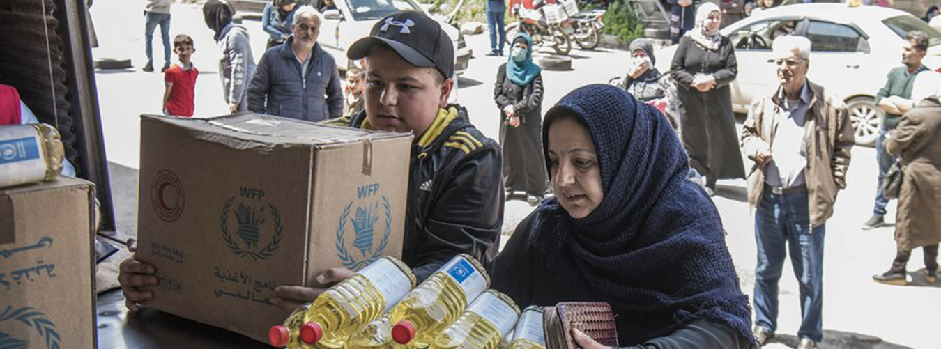 Une famille collecte des rations alimentaires à un point de distribution du PAM en Syrie.