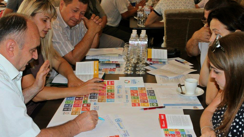 Un groupe de personnes autour d'une table regarde des brochures sur les ODD.