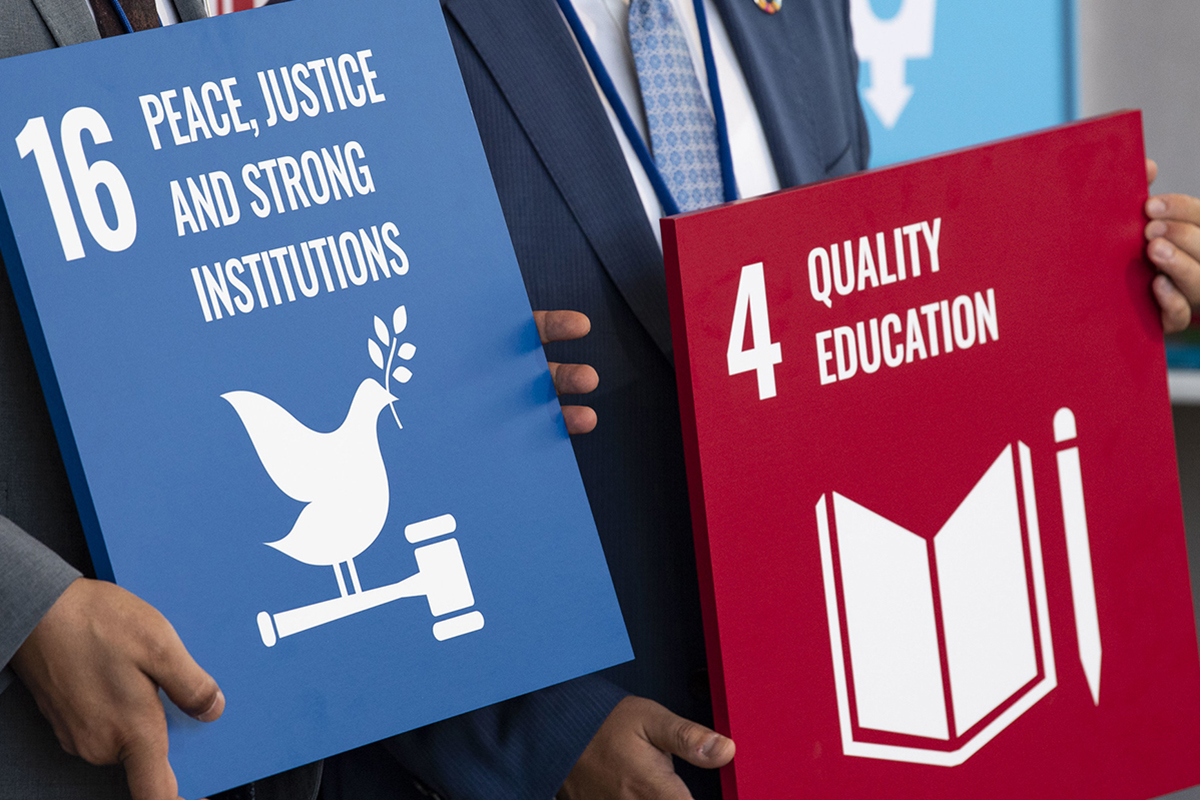 2 people holding Sustainable Development Goals 4 boards