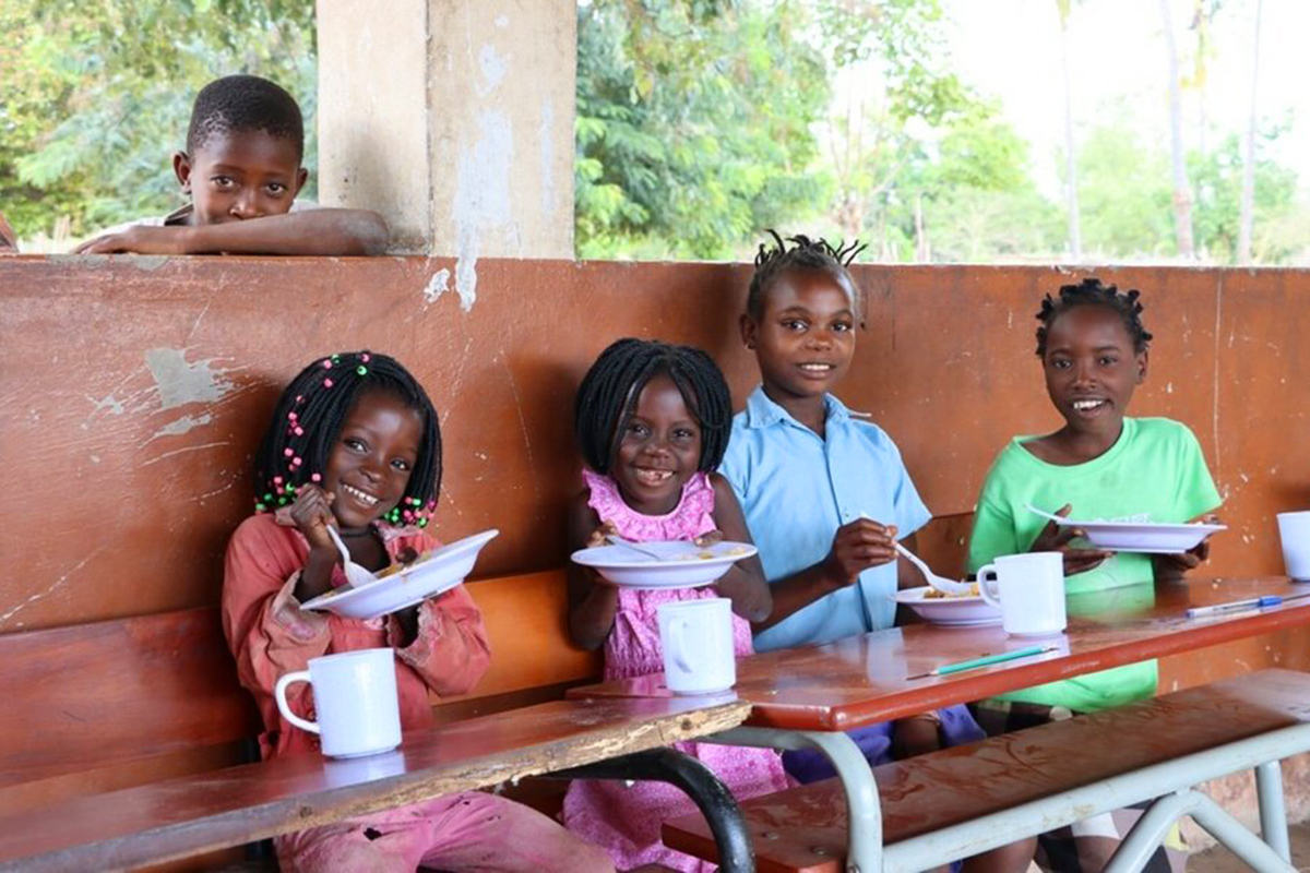 A group of smiling children eat at a table.