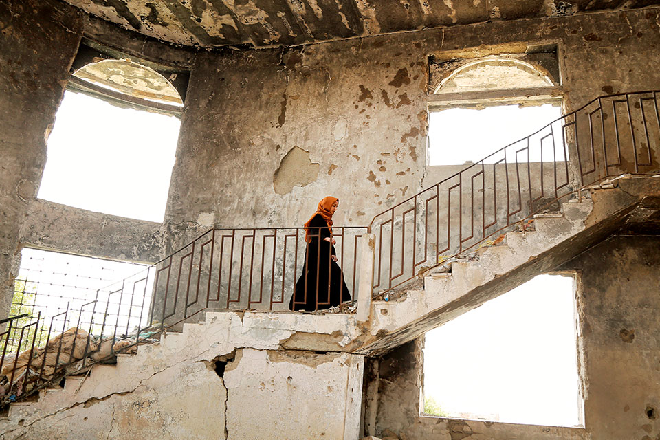 woman walking up stairs in damaged building