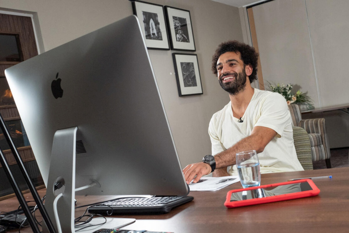 Mo Salah sits in front of a computer.