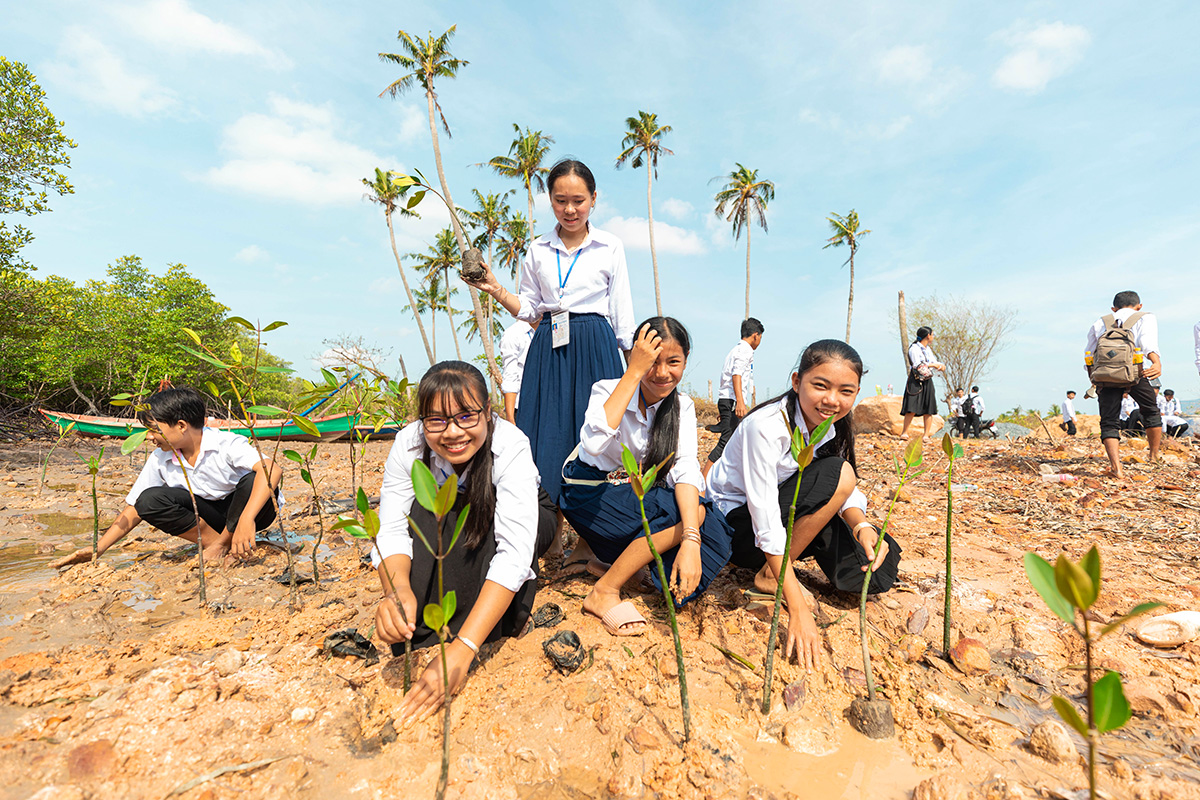 A group of girls in school uniforms planting trees.