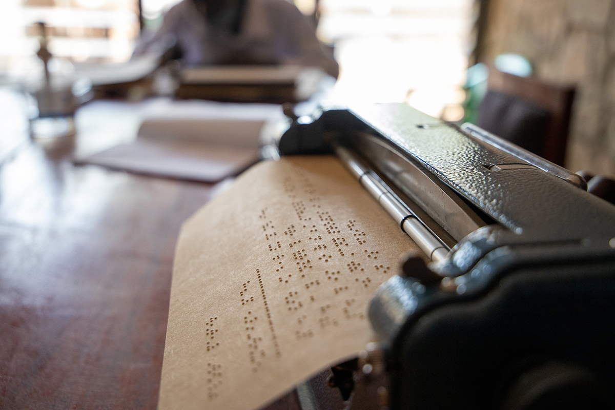 A piece of paper with braille character coming out of the back of a braille typewriter