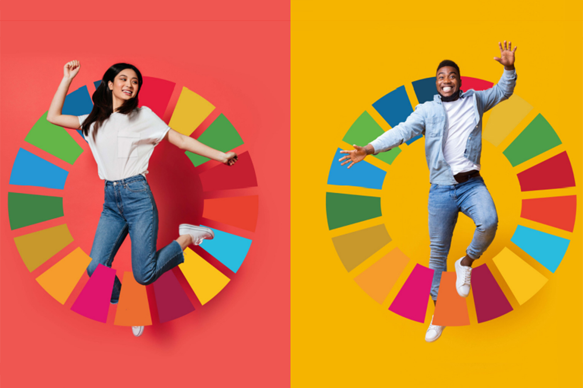 Two youths jumping with the SDG logo in the background.