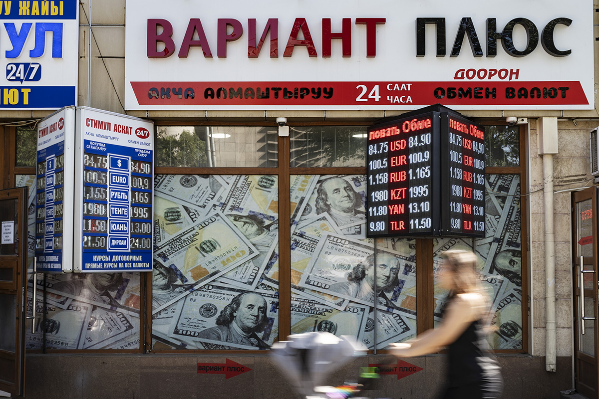 A woman walking by a foreign exchange office.