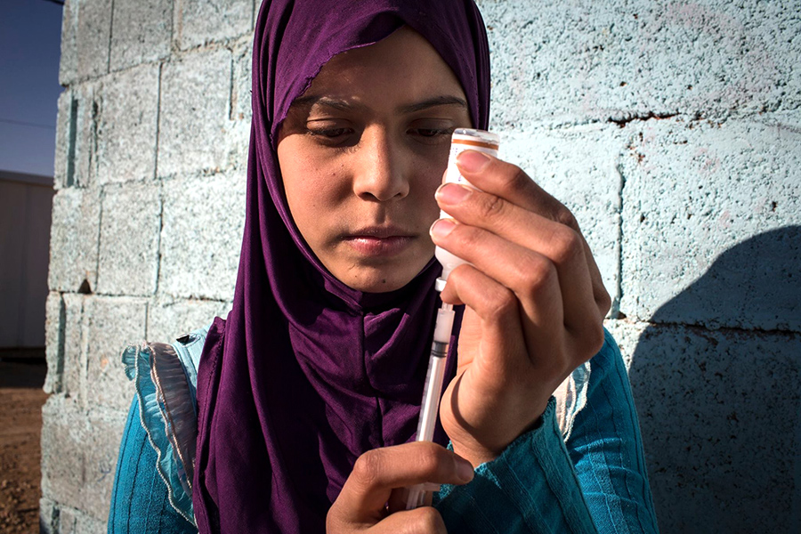 Girl draws insulin into a syringe. 