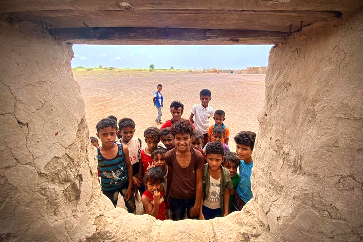 A group of children seen from the window of an old structure.