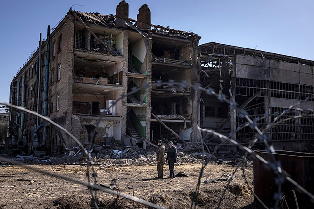 A destroyed building behind barbed wire