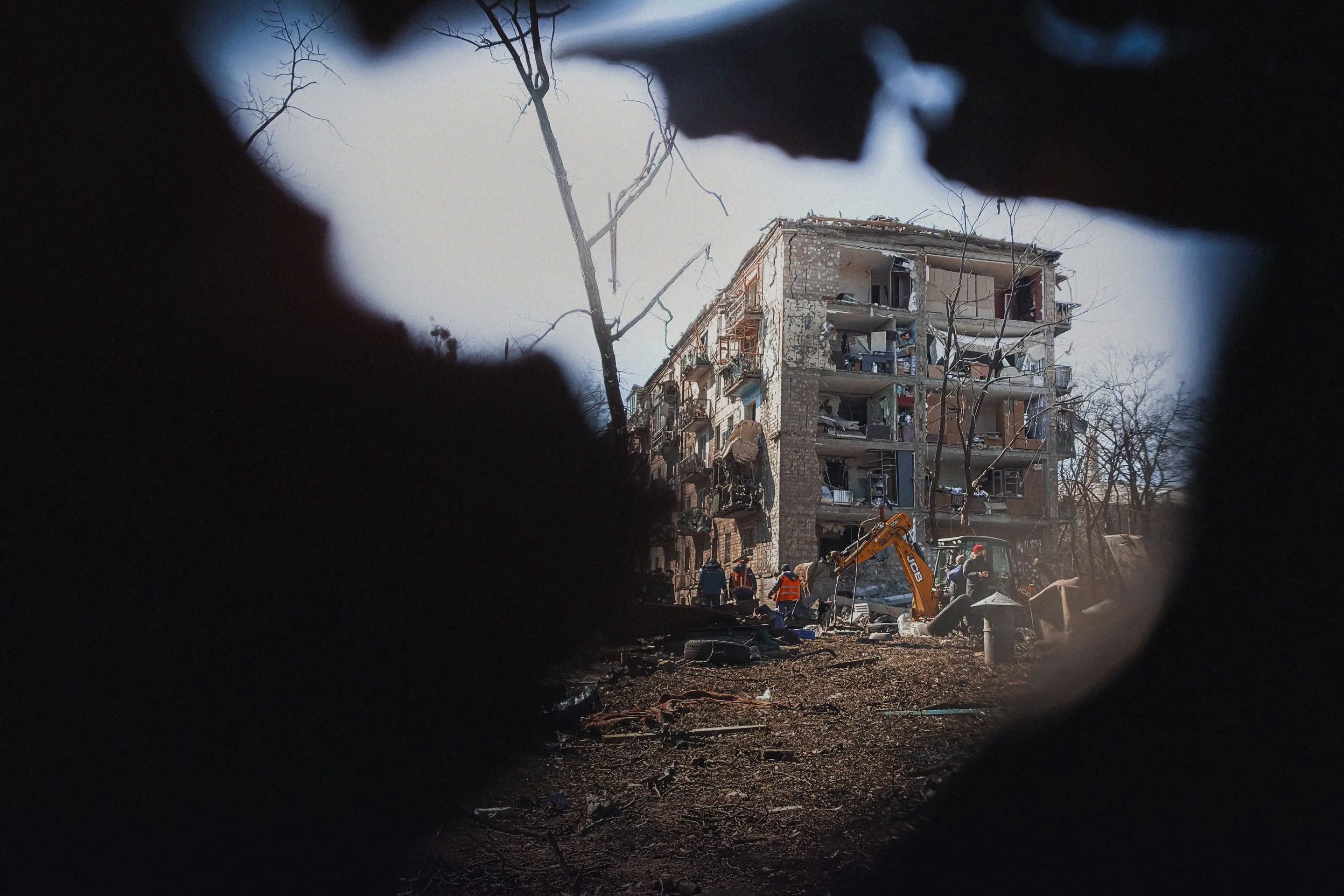 A building destroyed seen from a crack in a black foreground.