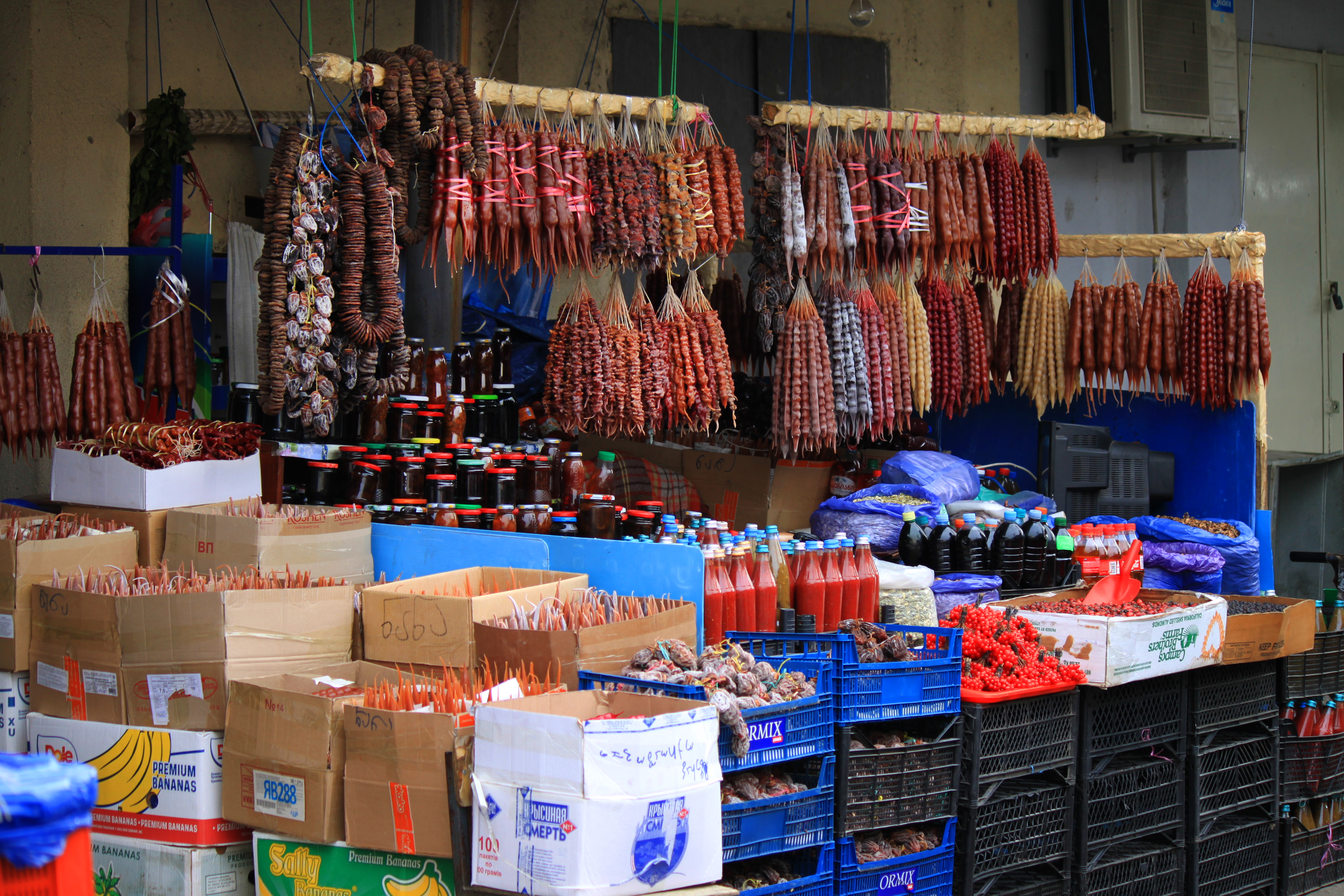 A market stall with a variety of stacked and hanging food.