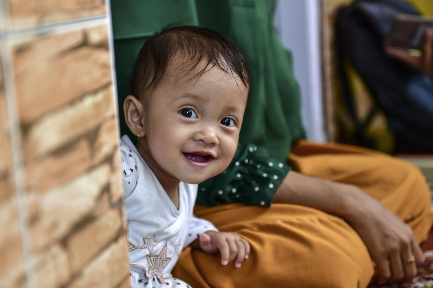 A smiling little girl peeks from behind a wall