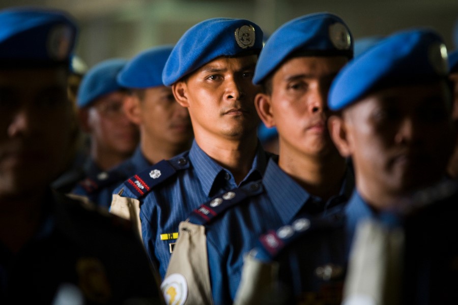 men stand in rows wearing the blue UN berret
