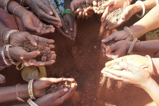 Hands forming a circle holding soil. 