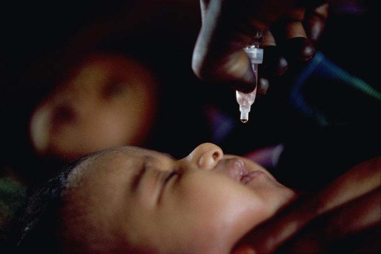 Baby lying down with vaccine drip above 