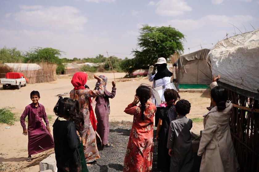 Women and children wave at a woman waving back.