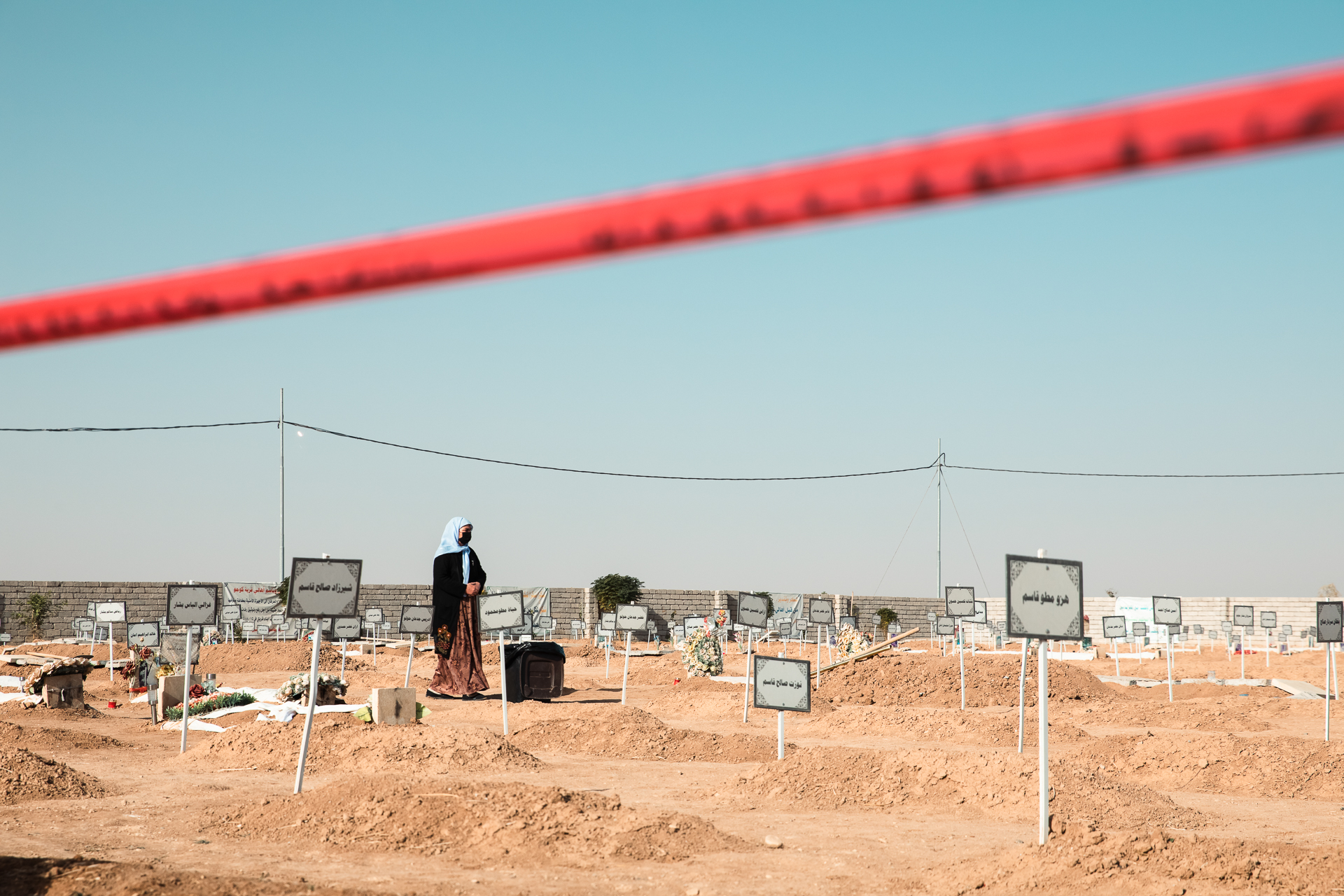 a woman walks along fresh graves