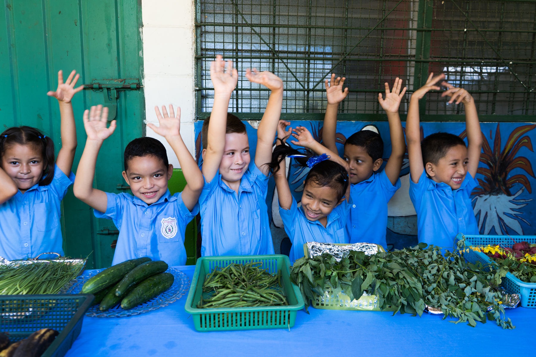 Children cheering with hands up and table full of healthy food 