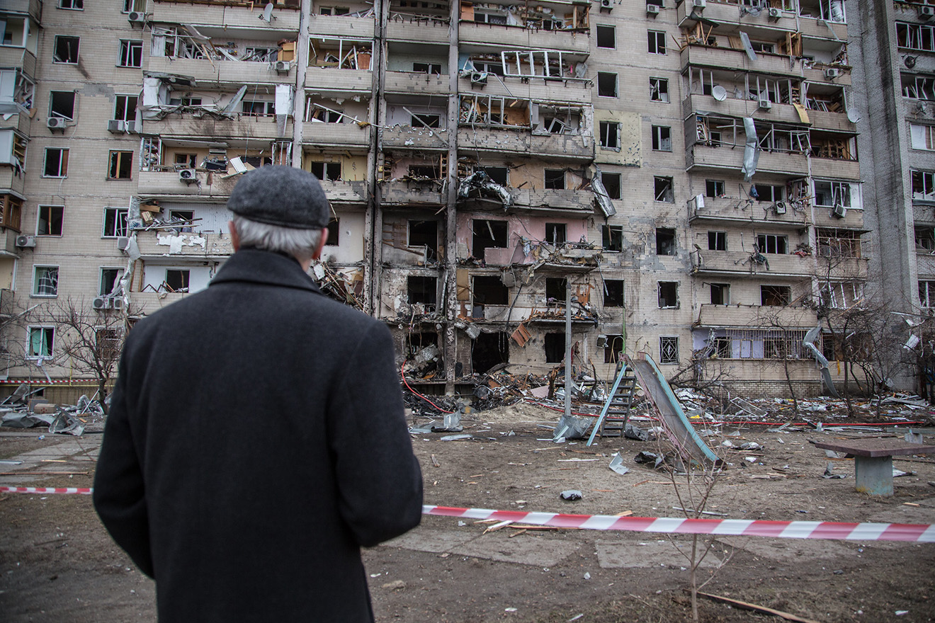 A man looking at a ruined residential building.