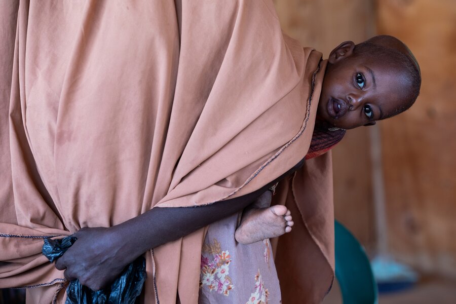 Women covered in pink blanket carrying baby