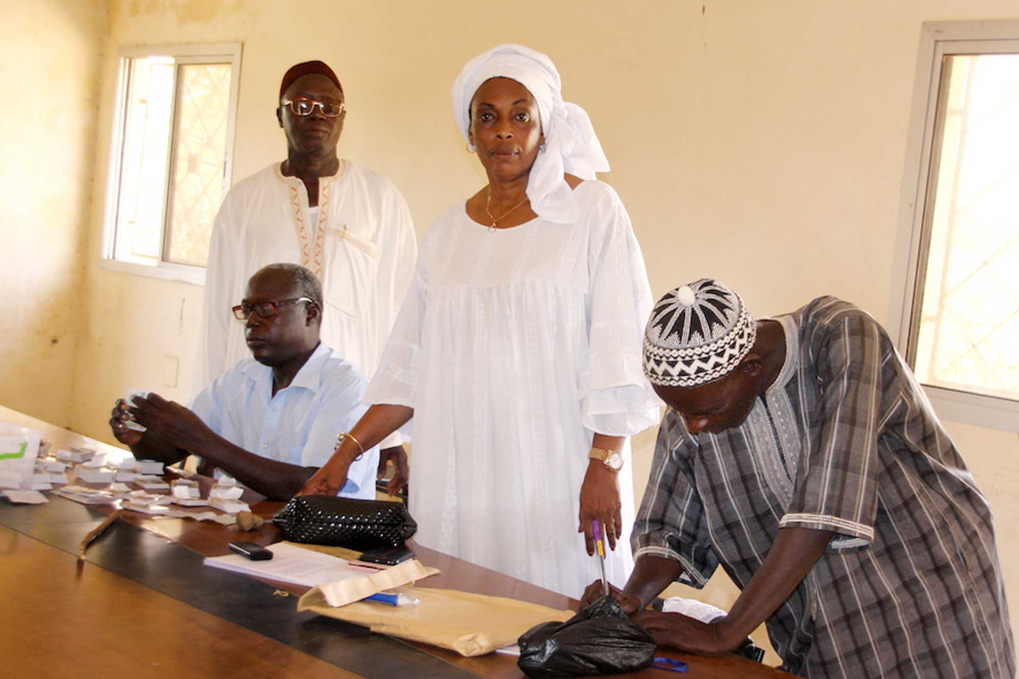 Coumba Diaw stands at a table with men next to her