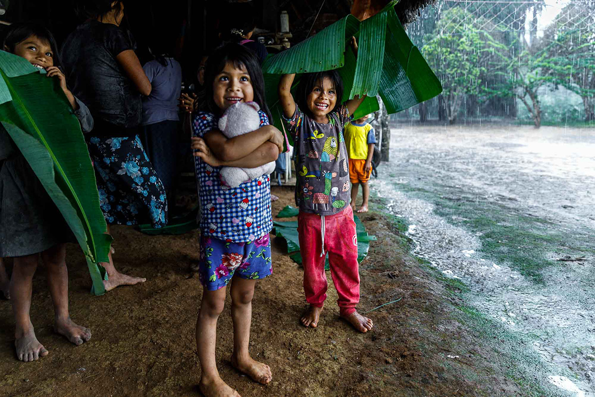 Two smiling girls hide from the rain