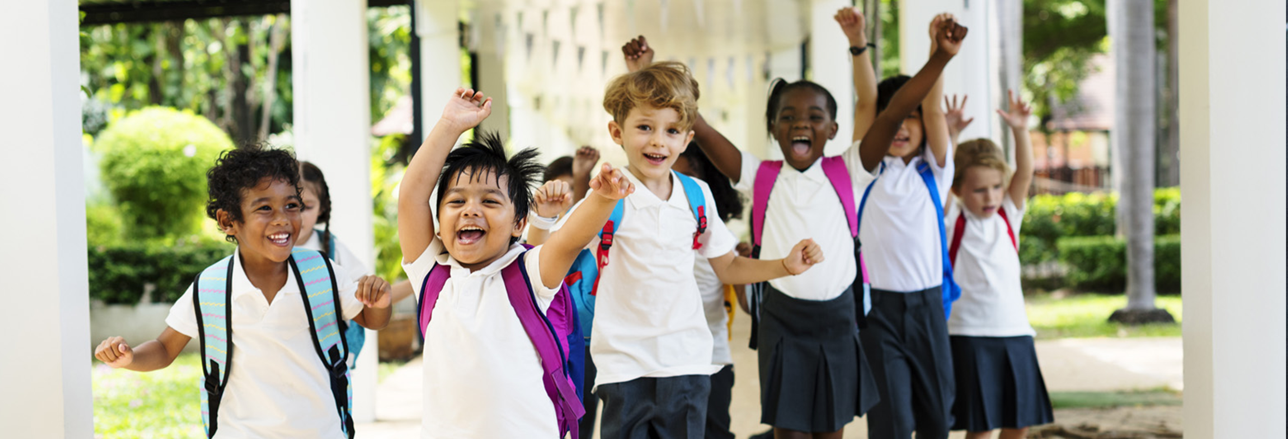 A line of school boys holding their arms up and yelling in joy