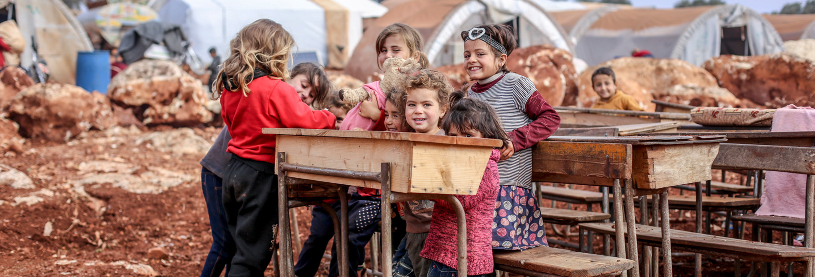 Three students smile in schoolyard