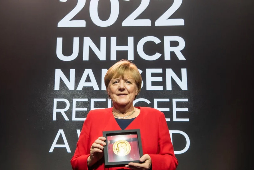 Dr. Angela Merkel holds a plaque.