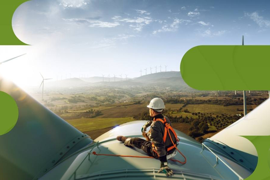 A man sits on to of a wind turbine and looks out at others. 