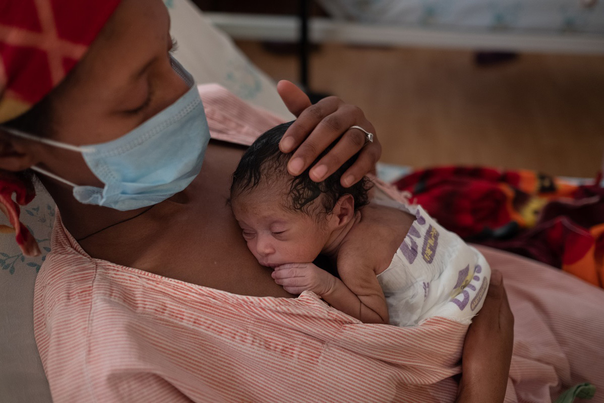 Mother carries a preterm baby against her chest.
