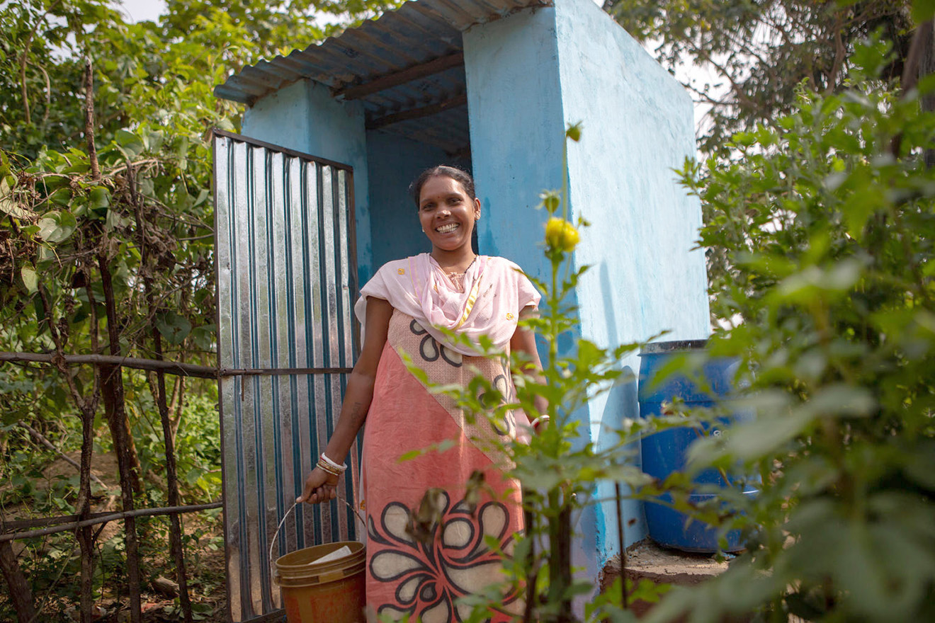 A woman smiles in front of a toilet installation