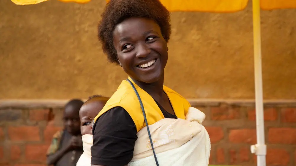 Woman with baby strapped to her a back. 