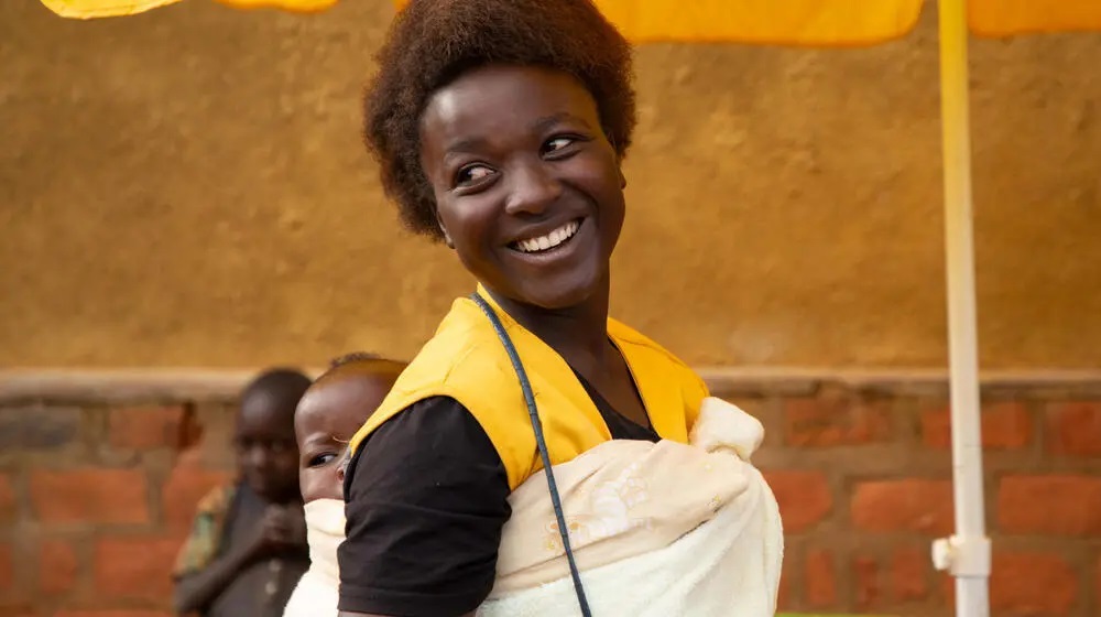 Woman with baby strapped to her a back. 