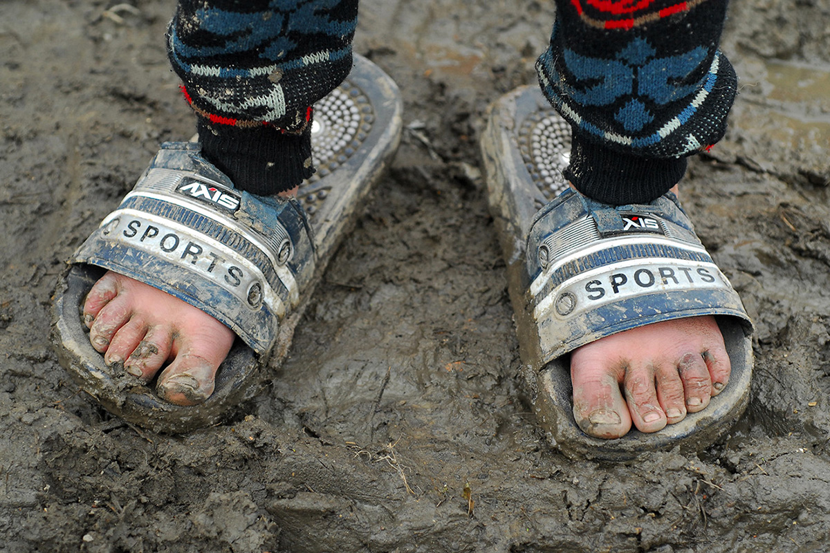 Dirty feet of a child with oversized flip-flops