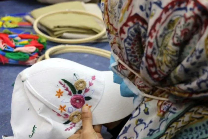 woman embroidering cap