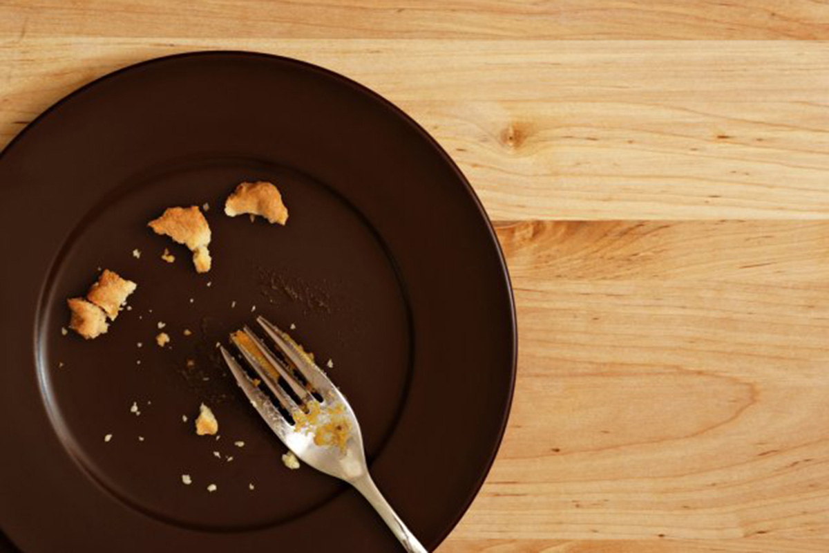 An almost empty dish with crumbs of food and a fork.