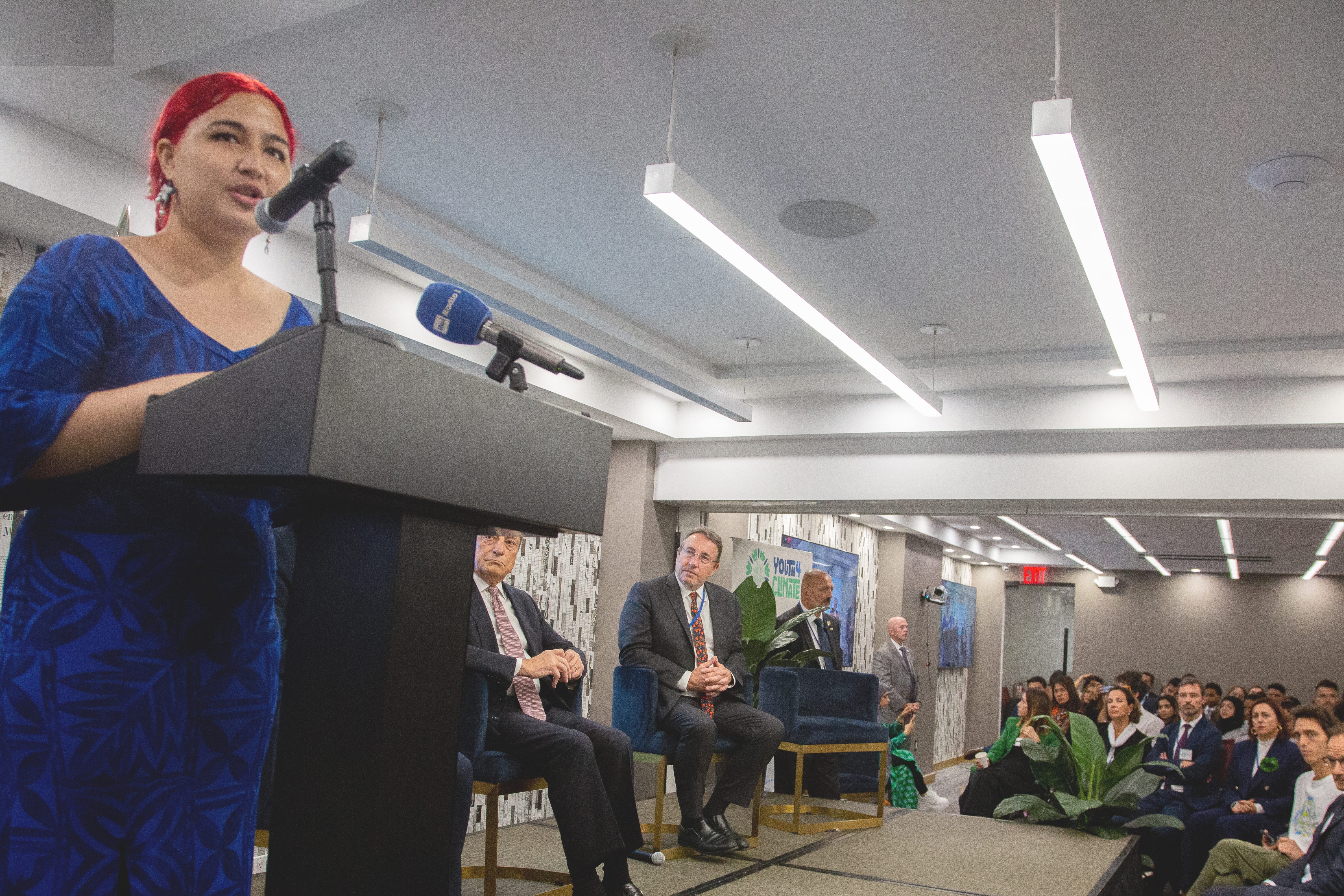 A young woman on a stage speaking to a crowd