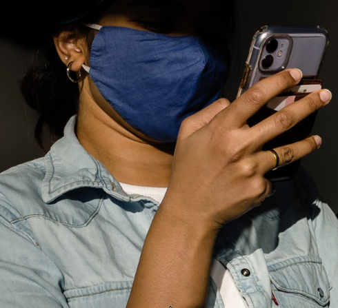 a young woman in the shadows looks closely at a smartphone screen