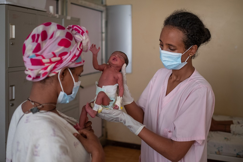 Une infirmière tient un nouveau-né et le montre à sa mère