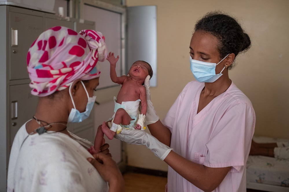 a nurse holds up a baby in front of the mother