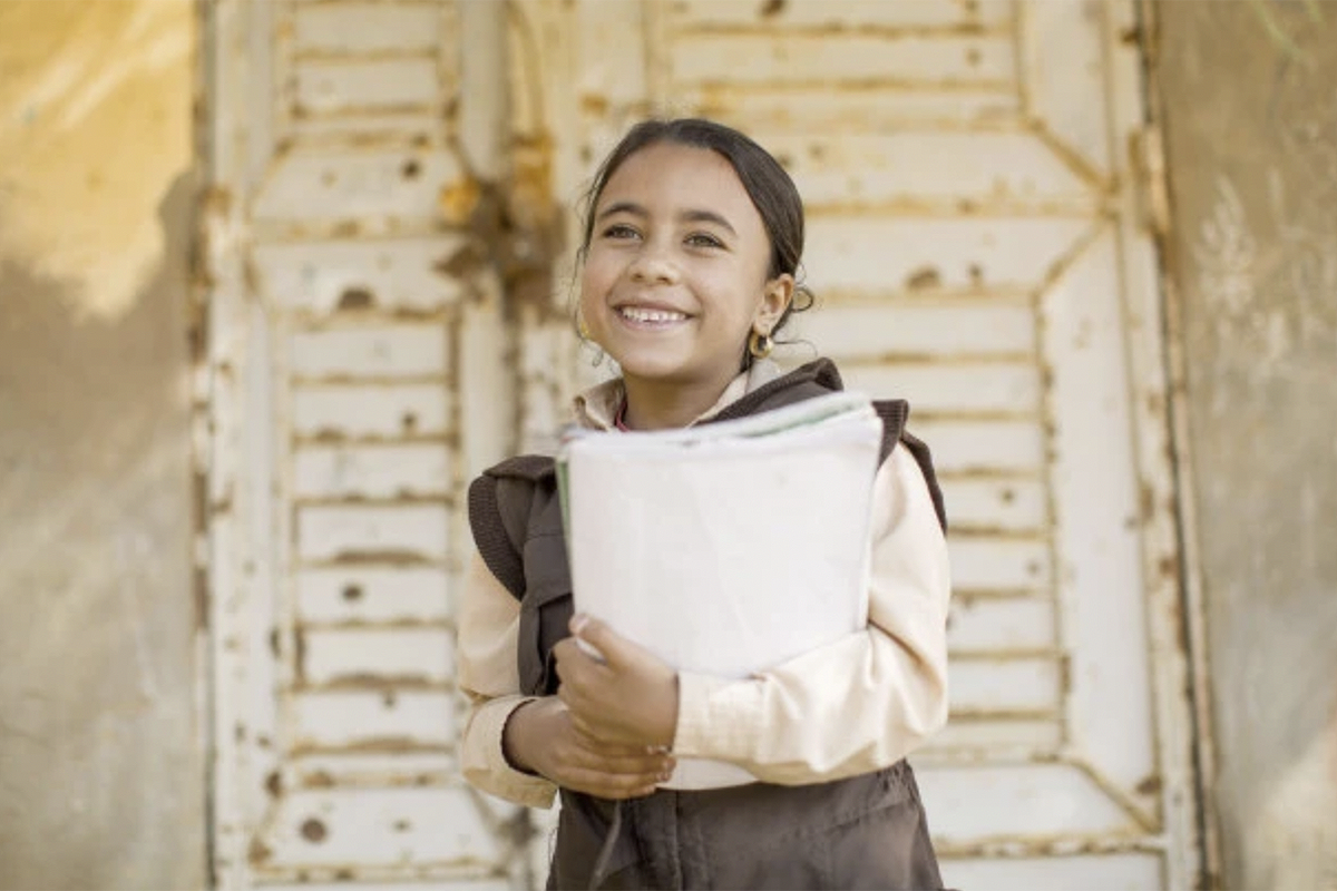 A girl smiles while holding her notebooks.