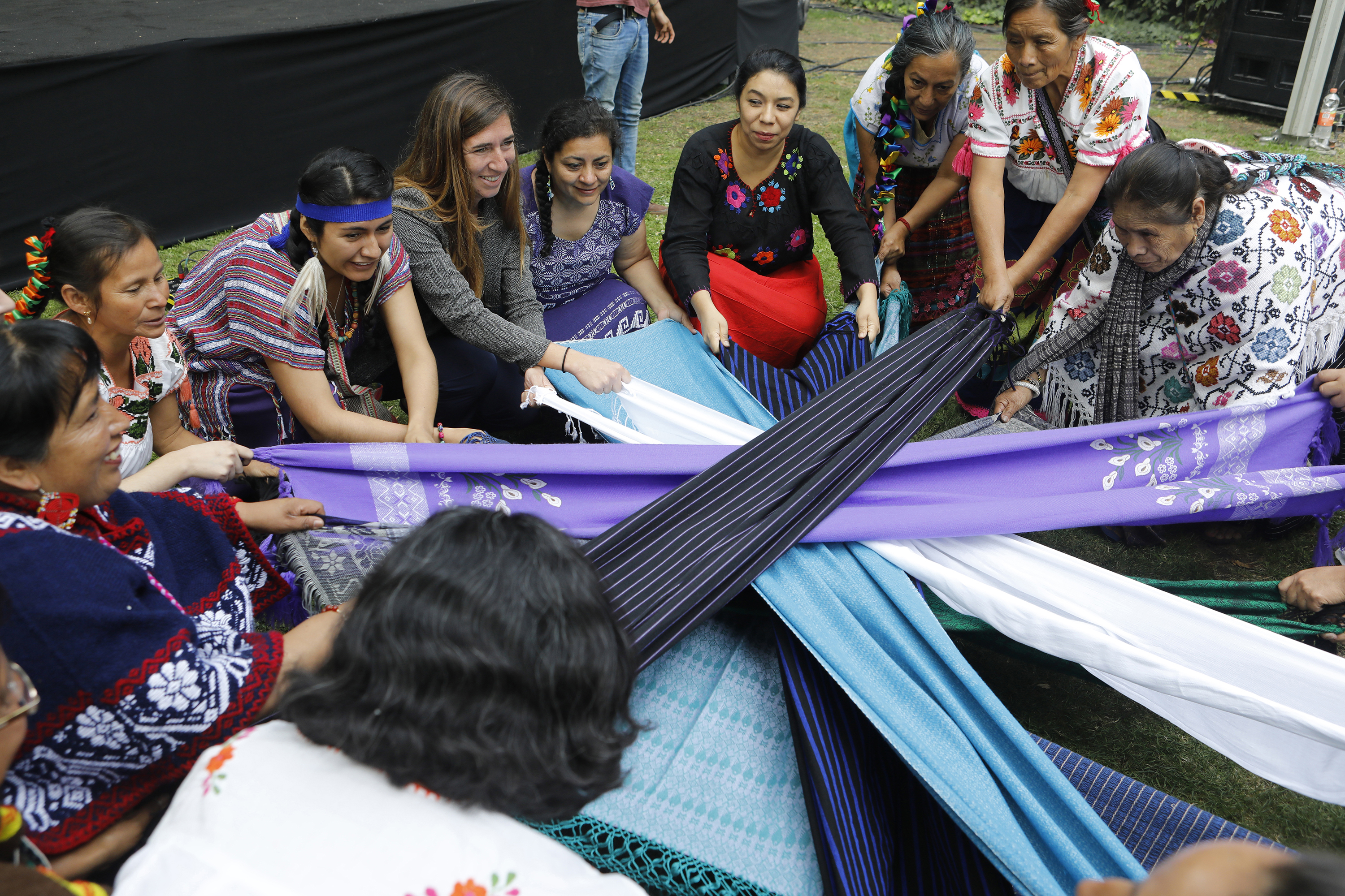 women hold opposite ends of different fabric stretching them into the shape of a star