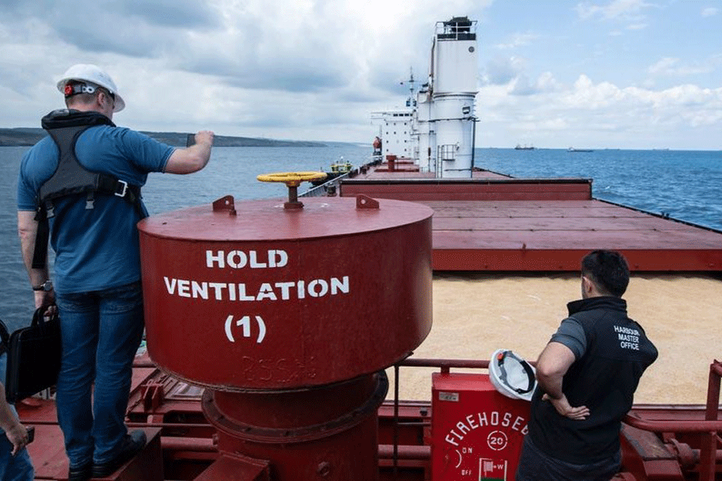 Three workers on a commercial vessel carrying grains. 