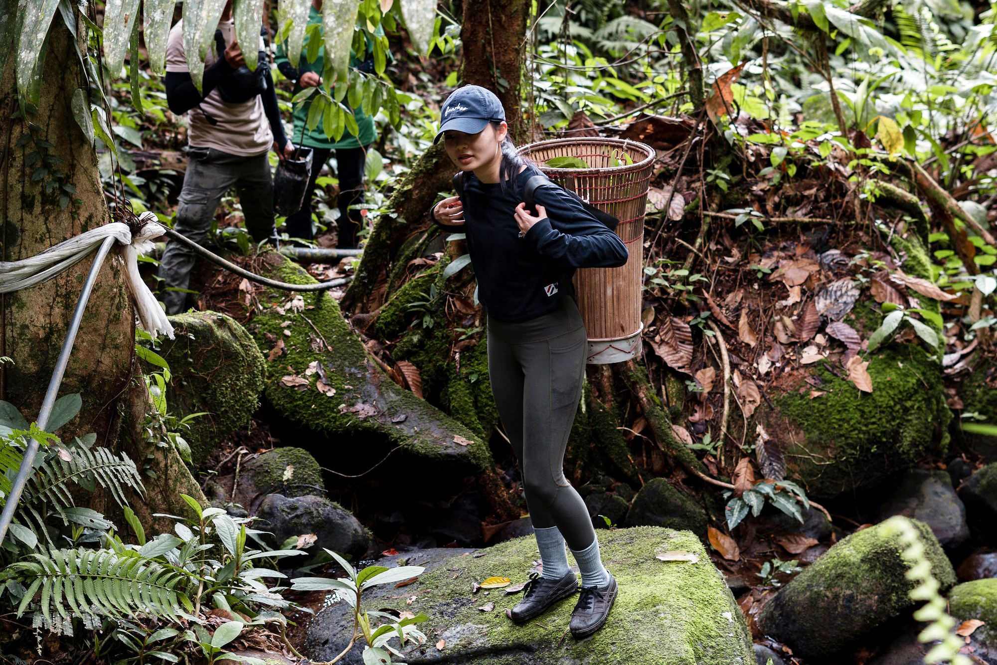 young woman with basket on her back standing on rocks