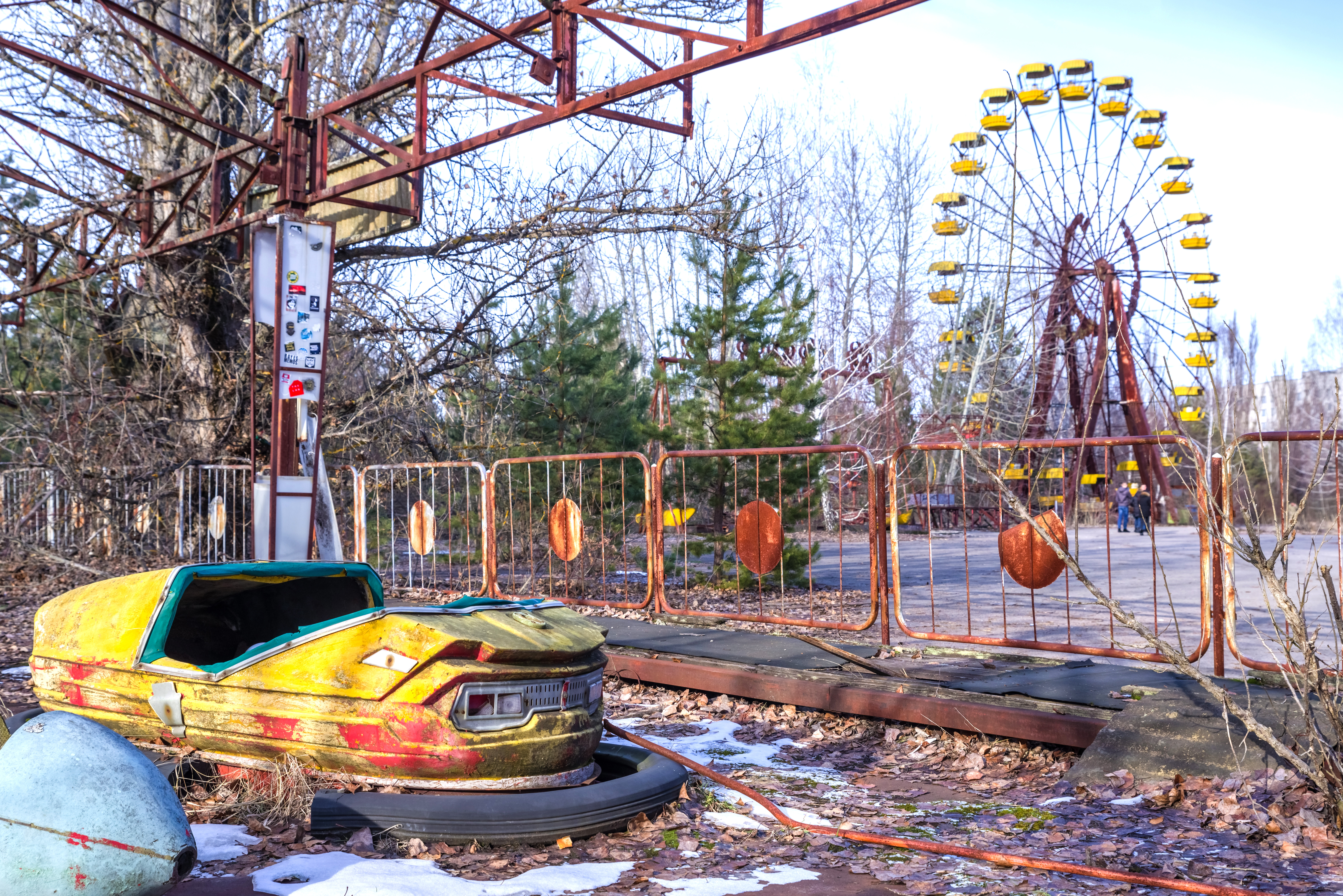 a bumper car in disrepair in front of an empty Ferris wheel