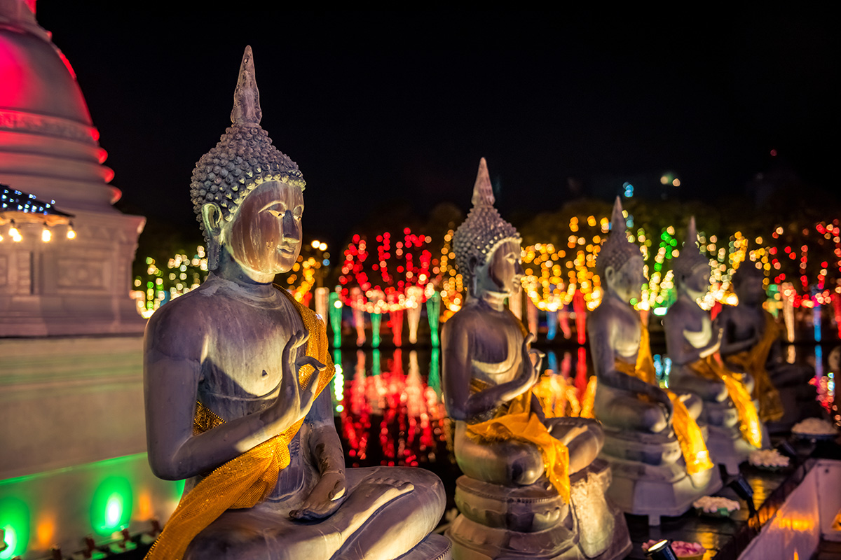 Statues of the Buddha surrounded by lights of different colours
