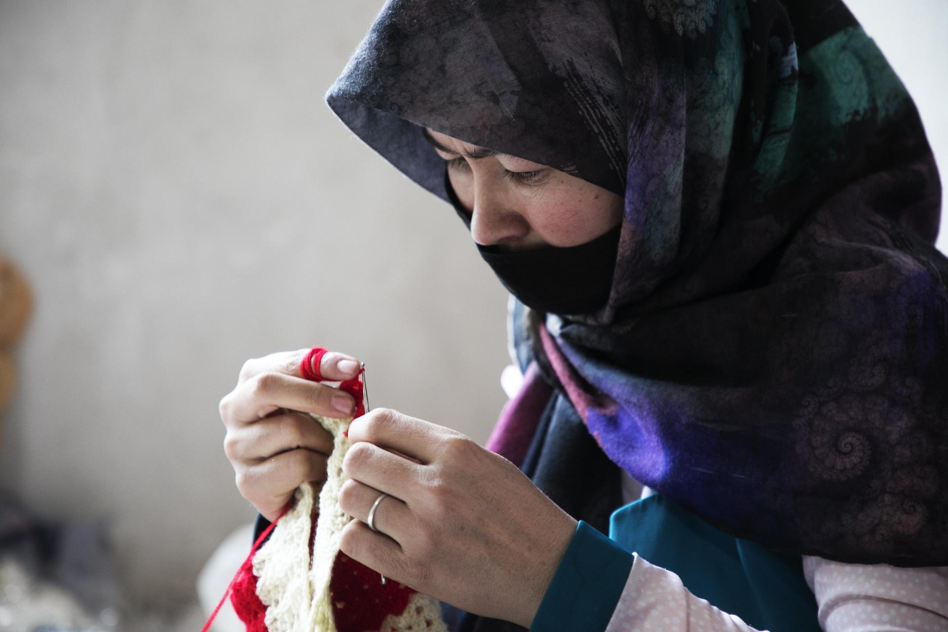 a woman looks down as she knits