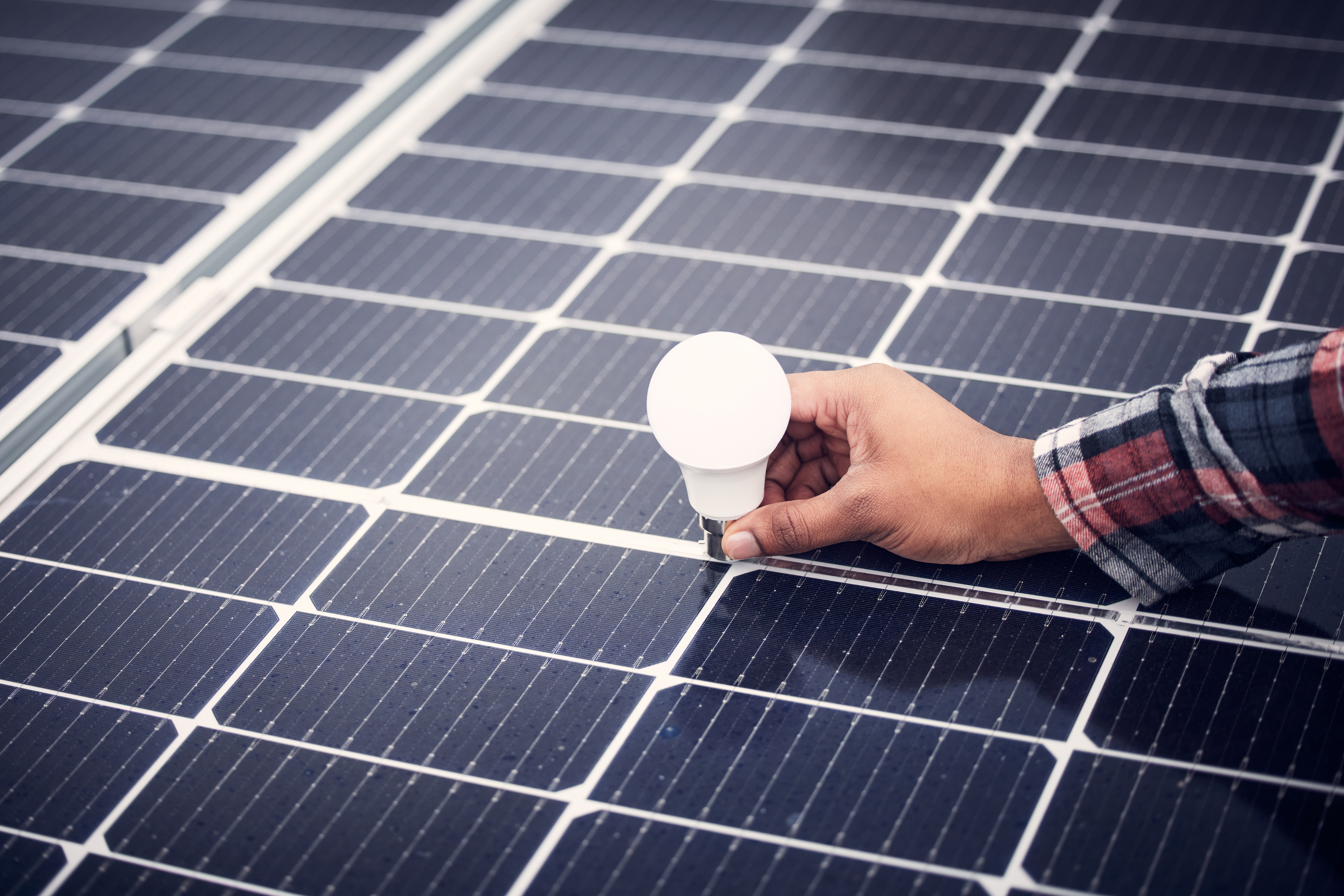 A lit lightbulb in direct contact with a solar panel