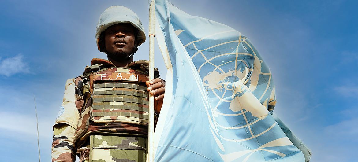 Un Casque bleu tenant le drapeau de l'ONU
